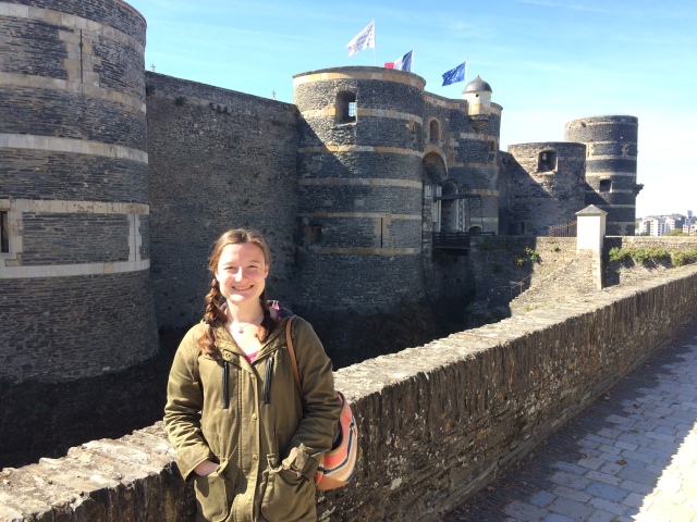 Young woman stands in front of the chateau d'Angers in Angers, France