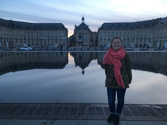Young woman stands in front of the Miroir d'Eau in Bordeaux, France